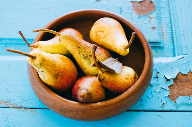 Fresh pears in a wooden plate on an old wooden