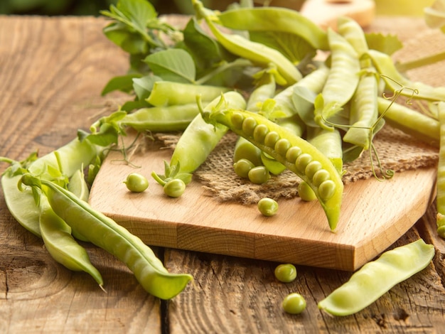 Fresh peas and their pods on an old wooden table rustic background with peas