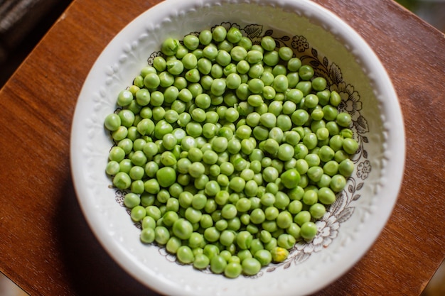 Fresh peeled green peas are in a plate.