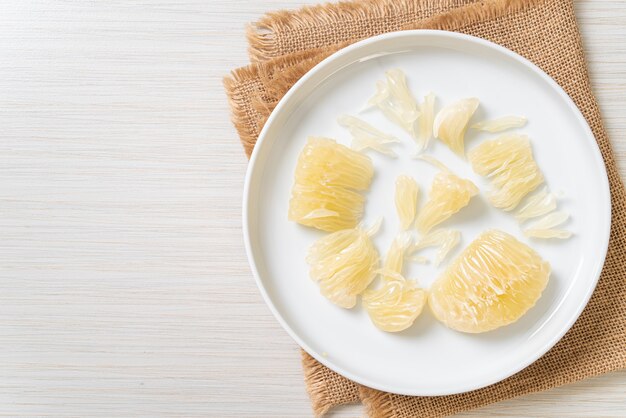 Fresh peeled pomelo, grapefruit or shaddock on white plate