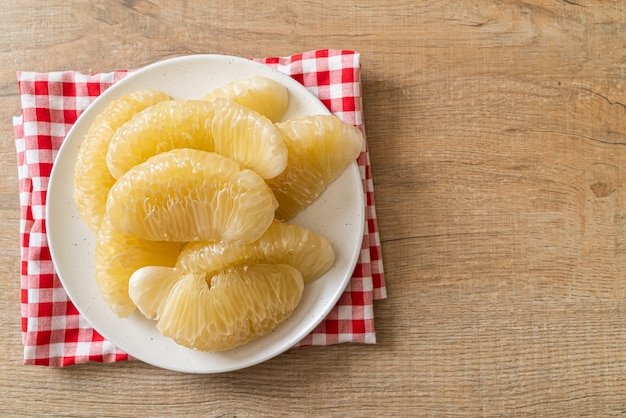 Fresh peeled pomelo, grapefruit or shaddock on white plate