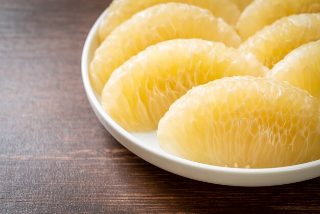 Fresh peeled pomelo, grapefruit or shaddock on white plate