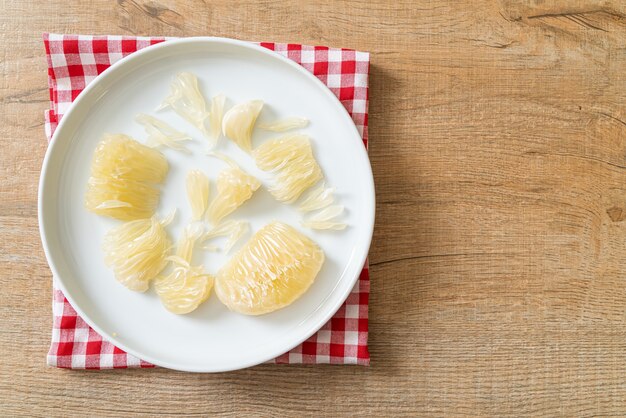 Fresh peeled pomelo, grapefruit or shaddock on white plate