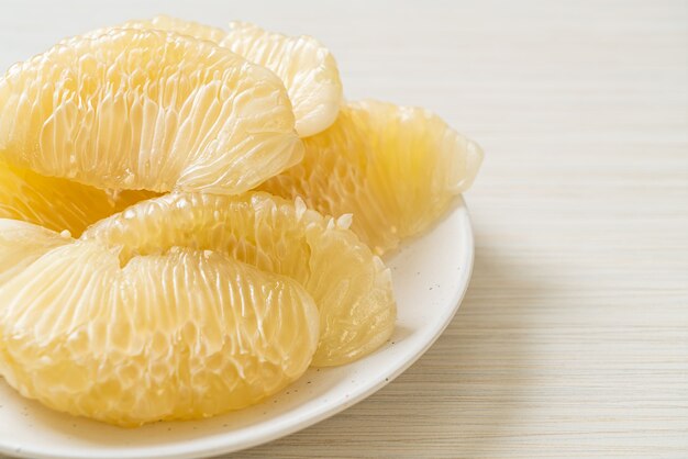 Fresh peeled pomelo, grapefruit or shaddock on white plate