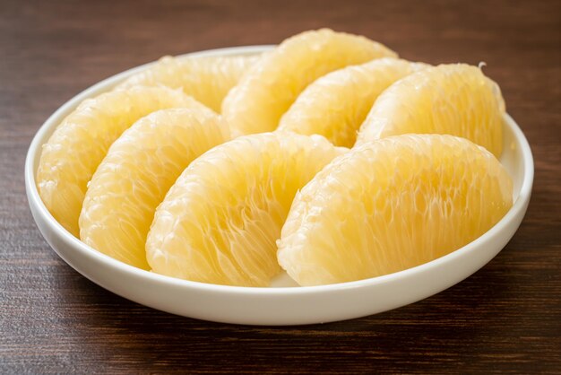 Fresh peeled pomelo, grapefruit or shaddock on white plate