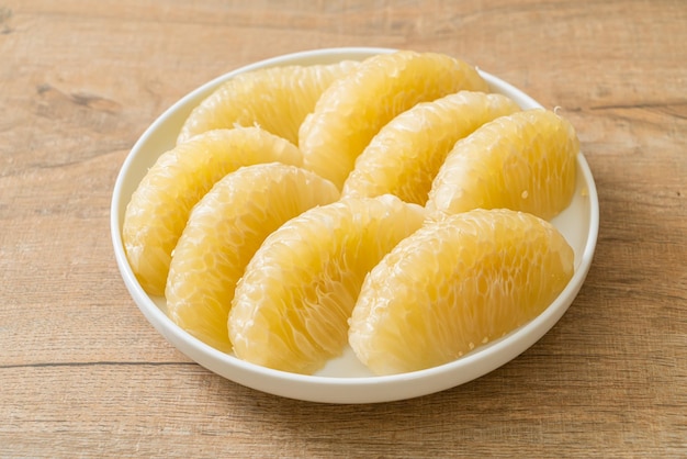 Fresh peeled pomelo, grapefruit or shaddock on white plate