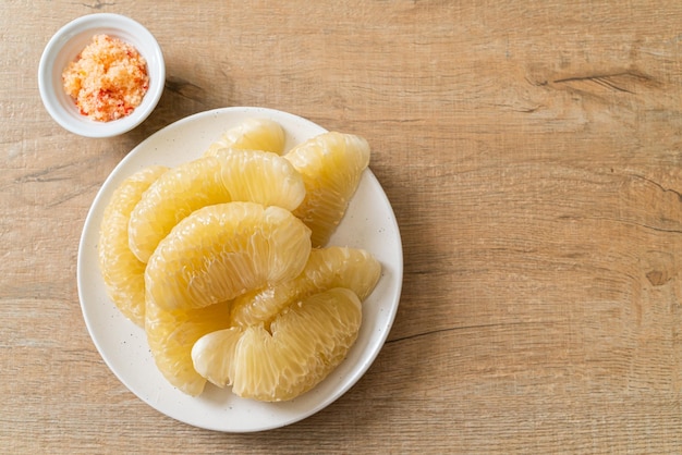 Fresh peeled pomelo, grapefruit or shaddock on white plate