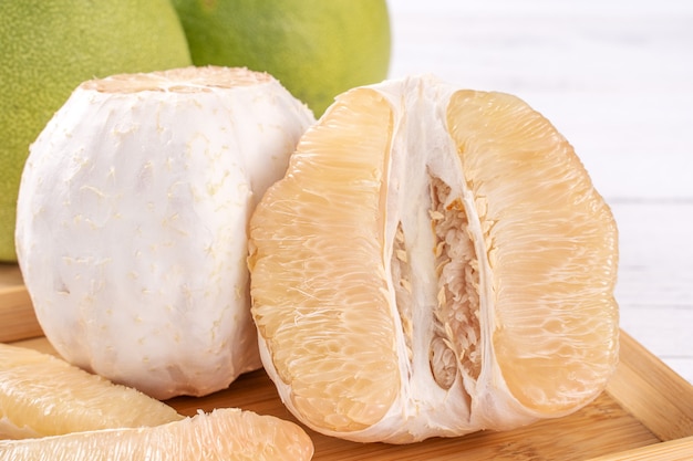 Fresh peeled pomelo, pummelo, grapefruit, shaddock on bright wooden table background. Seasonal fruit for Mid-Autumn Festival, close up, copy space.