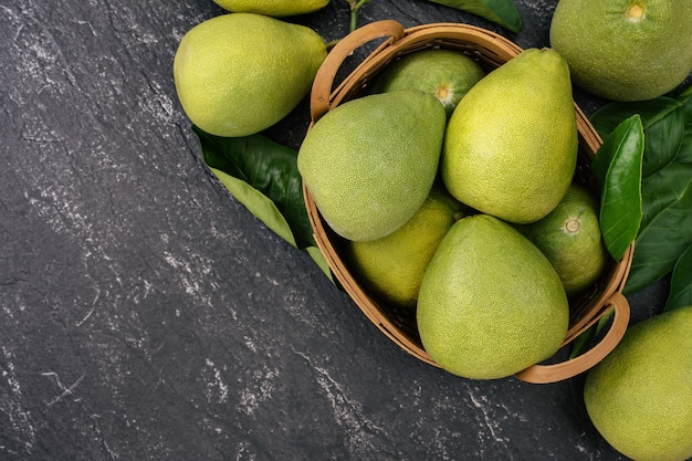 Fresh peeled pomelo, pummelo, grapefruit, shaddock on dark background in bamboo basket. Autumn seasonal fruit, top view, flat lay, tabletop shot.