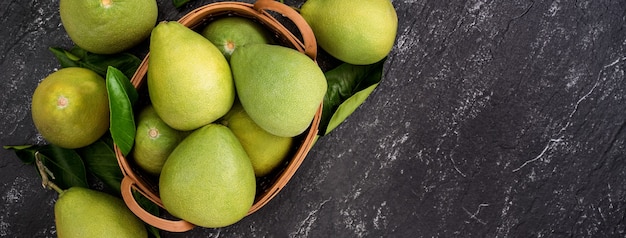 Fresh peeled pomelo, pummelo, grapefruit, shaddock on dark background in bamboo basket. Autumn seasonal fruit, top view, flat lay, tabletop shot.