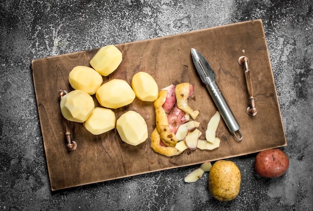 Фото Свежий очищенный картофель в старом лотке. на деревенском столе.