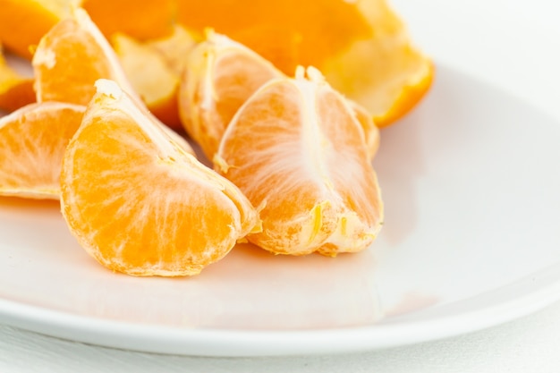 A fresh peeled tangerine on a white plate