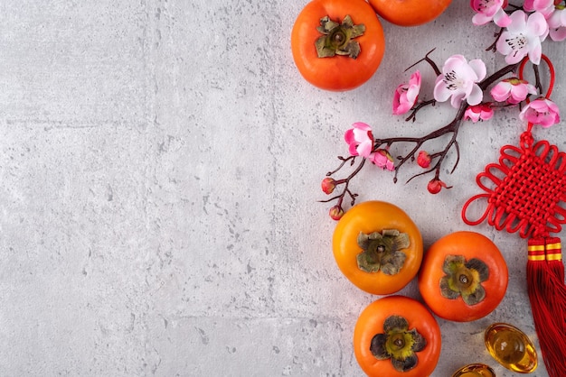 Fresh persimmons on gray table background for chinese new year fruit design, words on the golden coin means the dynasty name it made.