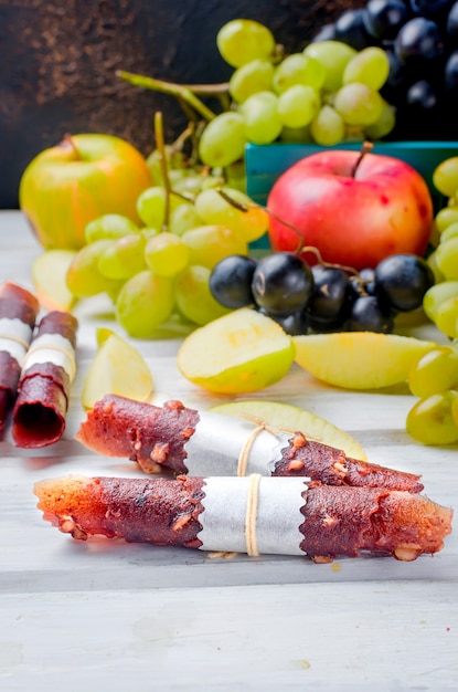 Fresh picked apples and grapes and fruits pastille on dark background