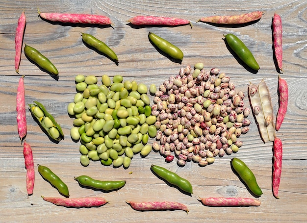 Photo fresh picked raw  beans (vicia faba) and bean pods  on an old wooden table.