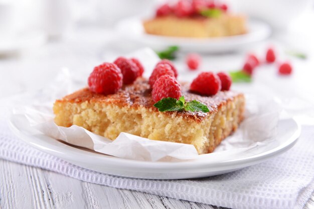 Fresh pie with raspberry in white plate on wooden table closeup