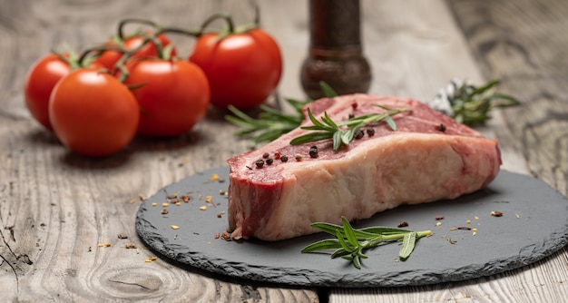 Fresh piece of beef, striploin steak on a black board with spices, close up