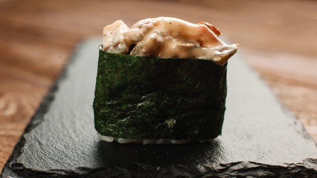 新鮮な美味しい寿司マキを黒スレートでお召し上がりいただけます。 1つのおいしい日本のロール、クローズアップビュー。伝統的な健康食品。