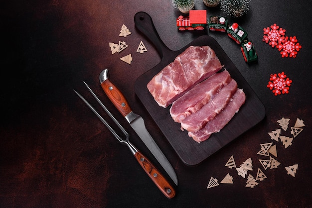 Fresh piece of raw pork with spices salt and herbs on a wooden cutting board