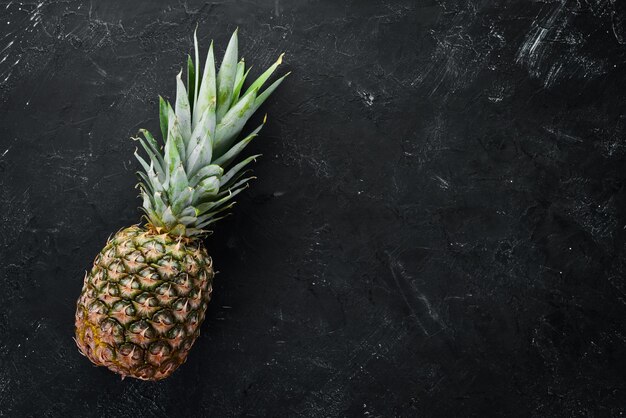 Fresh pineapple on a black stone background Top view Free copy space