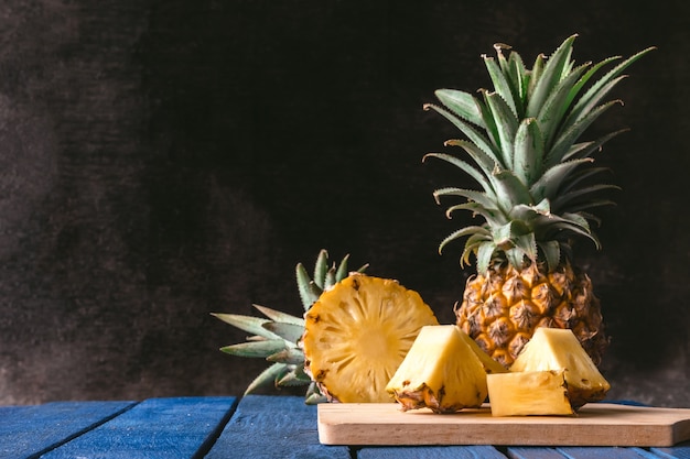 Fresh Pineapple fruit on blue wooden table with black background.