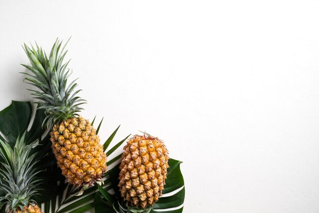 Fresh pineapple with tropical leaves on white background