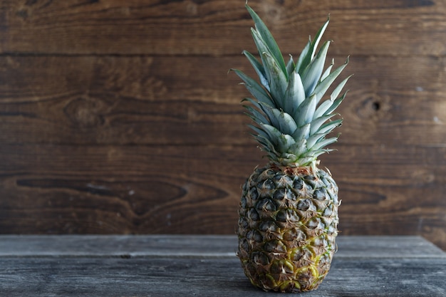 Fresh pineapple on a wooden table with a wooden board