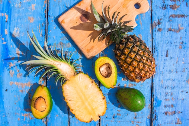 fresh pineapples and ice cubes on a blue wooden background