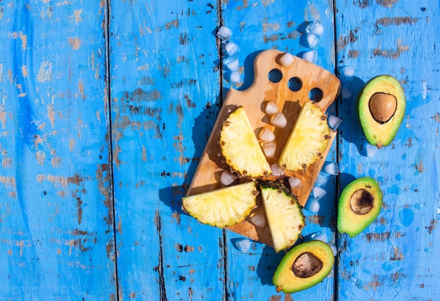 fresh pineapples and ice cubes on a blue wooden background