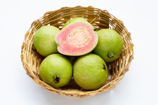 Guaiava rosa fresca in cesto di bambù su sfondo bianco.