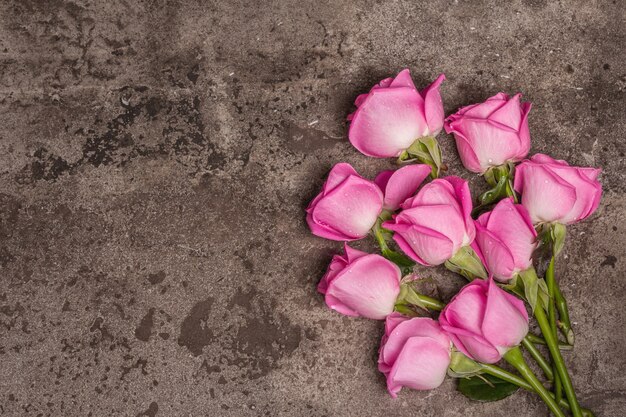 Fresh pink roses on textured stone concrete background. Greeting card for Weddings, Birthdays, March 8th, Mother's, or Valentine's Day