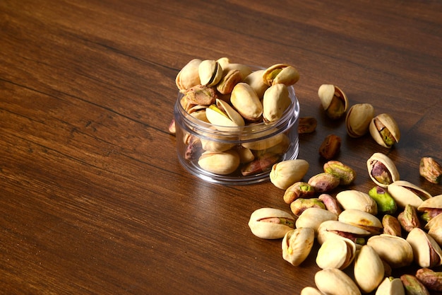 Photo fresh pistachio in the wooden bowl, organic, border white background, wooden background.