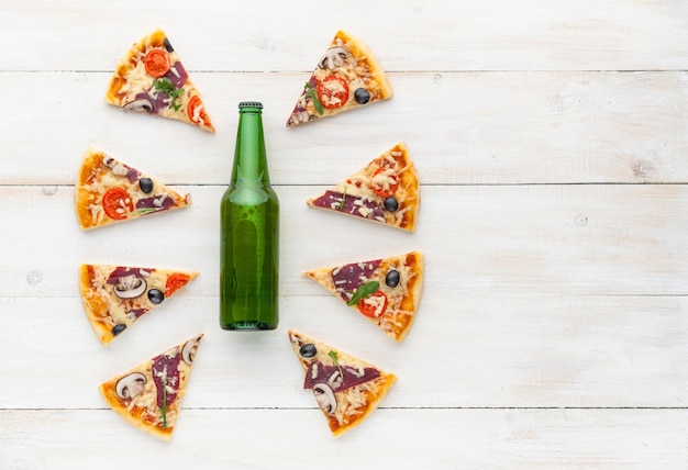 素朴なイタリアンスタイルの新鮮なピザ、ぎくしゃくしたオリーブのキノコと3種類のチーズ、明るい色の木製の背景に冷たいビールのボトル