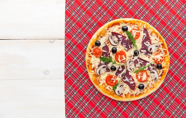 Photo fresh pizza in a rustic italian style with jerky olives mushrooms and three kinds of cheese on a light wooden background