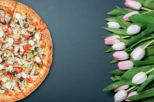 Fresh pizza and spring flowers tulips.