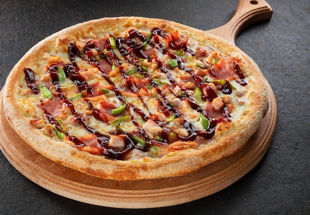 Fresh pizza with BBQ sauce on wooden cutting board