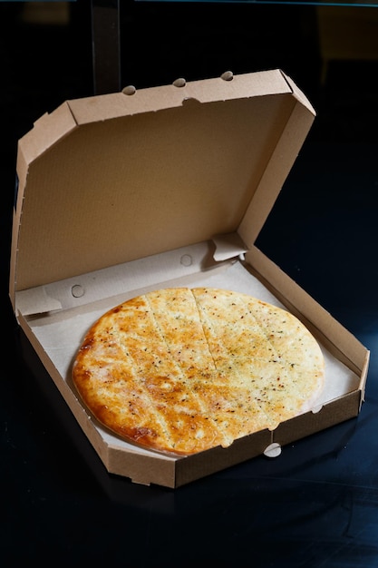 Fresh pizza with cheese in a cardboard craft box freshly baked pizza