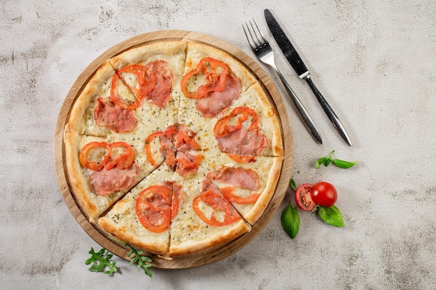 Fresh pizza with meat and ham on the concrete background