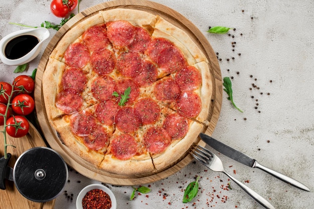 Fresh pizza with meat and ham on the concrete background