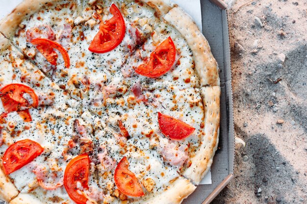 fresh pizza with tomato chicken and spices on the seashore sand food at the resort