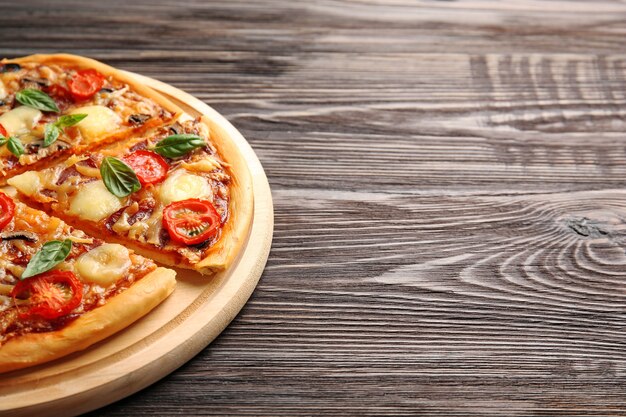 Fresh pizza with tomatoes, cheese and mushrooms on wooden table