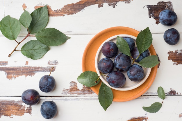 Fresh plum berries on a plate with leaves