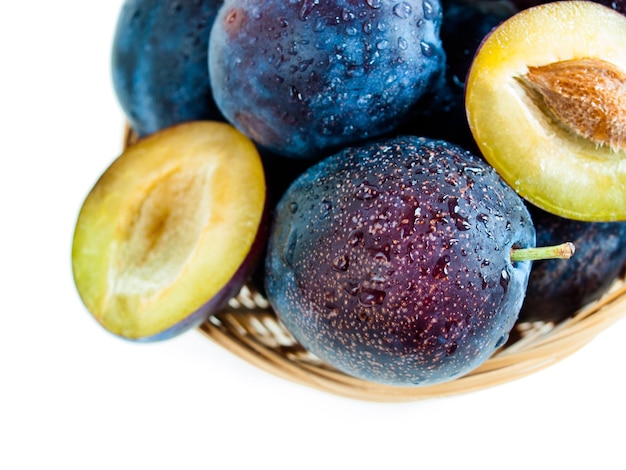 Fresh plums in basket on white background.