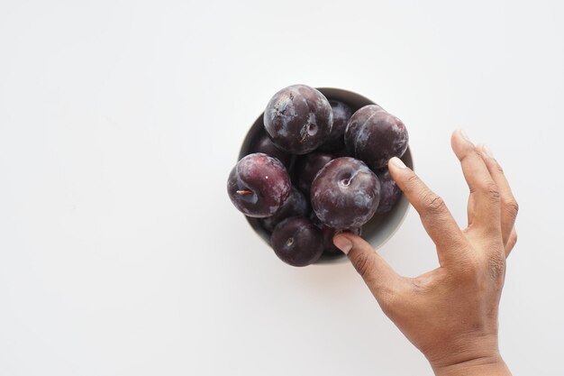 Fresh plums in a bowl on table