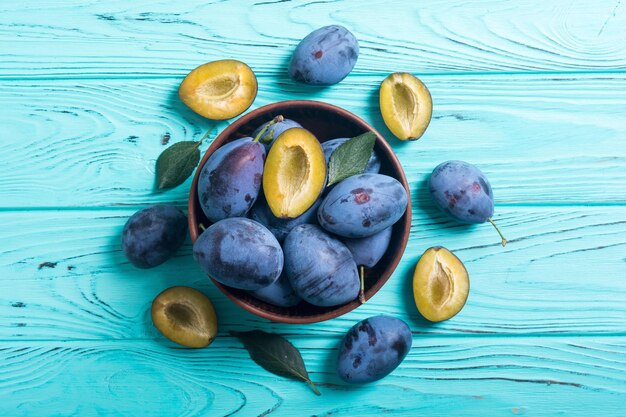 Fresh plums in bowl on wooden table Fruit background