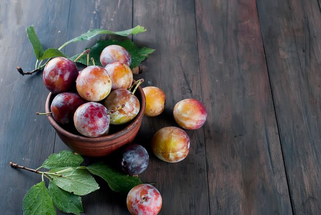 Fresh plums from garden in bowl on old wooden table.