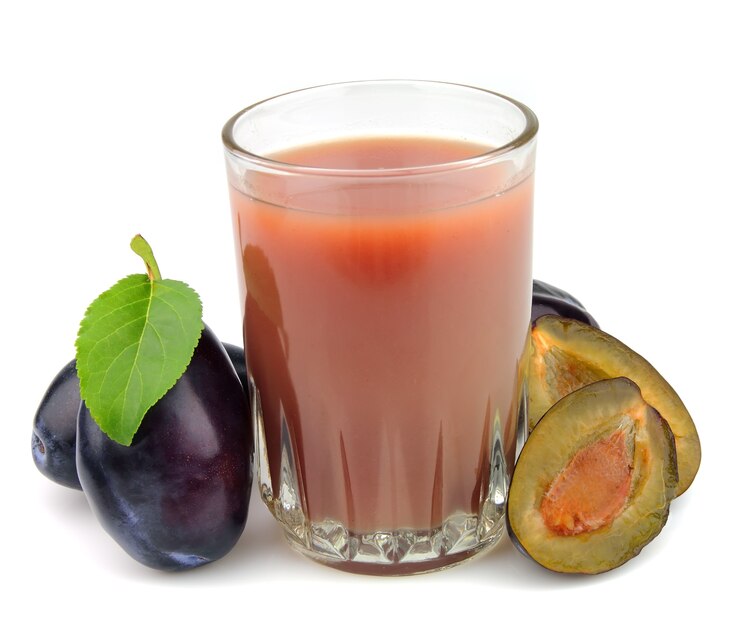 Fresh plums and a glass full of plums juice on a white background
