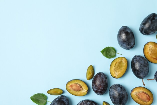 Fresh plums and leaves on table