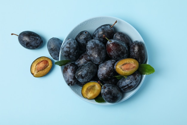 Fresh plums and leaves on table