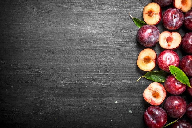 Fresh plums with leaves. On the black chalkboard.